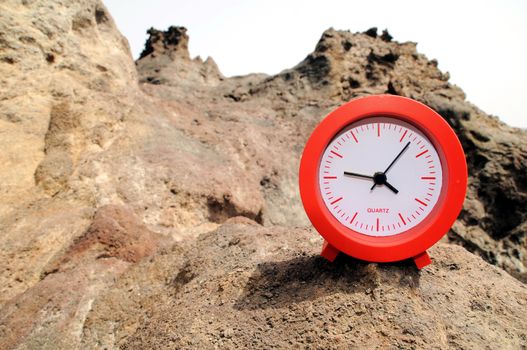 One Red Clock on the Rocks Near the Ocean 