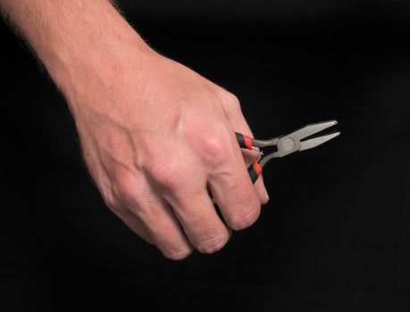 Hand and Strong Pliers over a Black Background