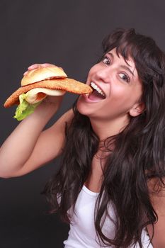 Young woman eating a sandwich with meat and salad