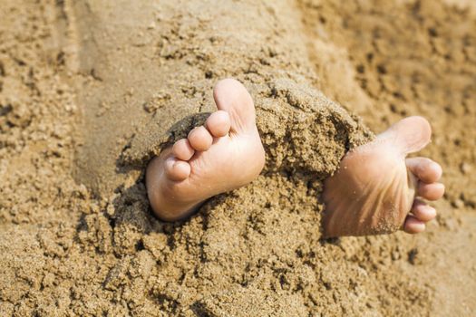 Child's feet in the sand close-up