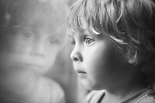 Little boy looking through window.