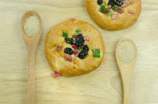 top view of two  bread with raisin and  dried fruits , and two  spoon of sugar on wooden background 