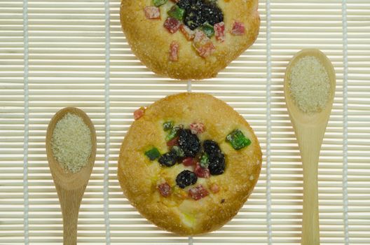 two  bread with raisin and  dried fruits and two spoon of sugar  on wooden background