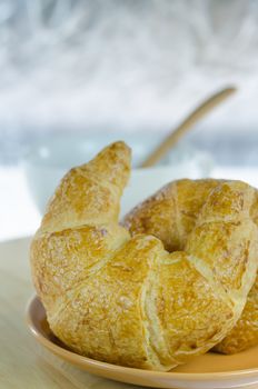 close up  croissants on  dish  and a white  cup of coffee with spoon