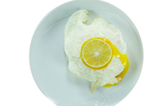 top view fried egg with slices of lime  on white dish over white background