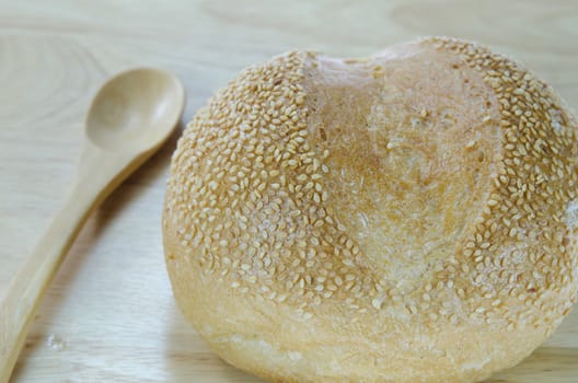 fresh rolls bread with sesame seeds with wooden spoon on wooden background