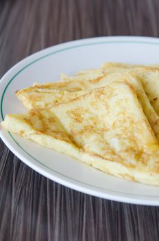 slices of french toast  on a white plate over wooden background