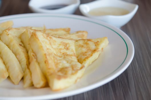 slices of french toast on a white plate served with  with sweet sauce