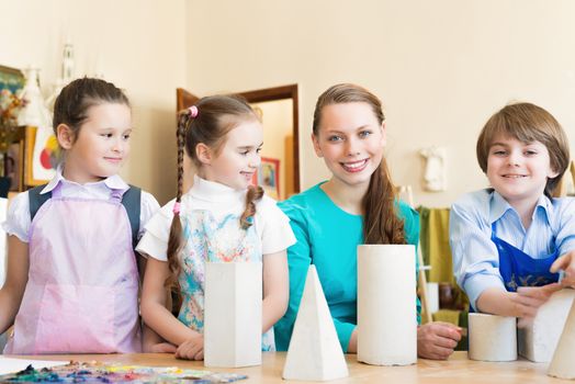 children with the teacher engaged in painting at an art school