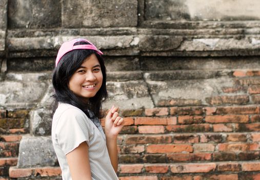 Pretty girl posing and smiling while standing near brick wall background