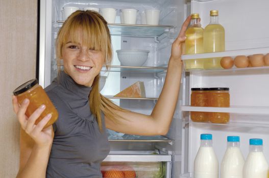 Mature woman looking for something in the fridge at home 