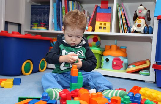 A baby boy playing with plastic blocks on the floor