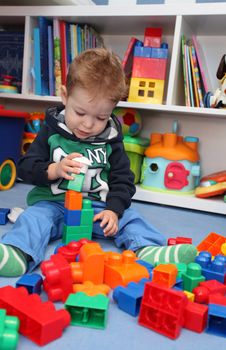 A baby boy playing with plastic blocks on the floor