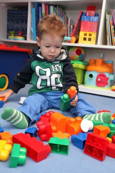 A baby boy playing with plastic blocks on the floor