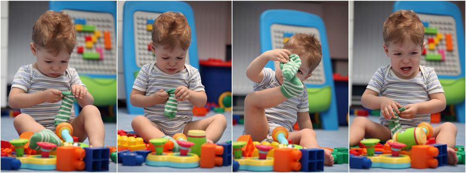 A funny baby boy trying to dress socks in children's room