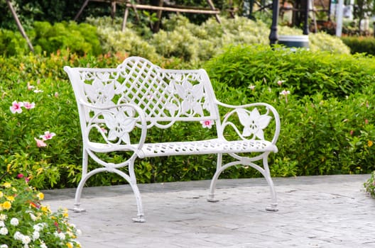White iron chair in garden with trees.