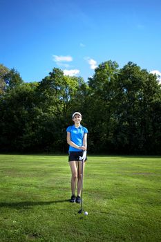 Pretty girl playing golf on grass in summer