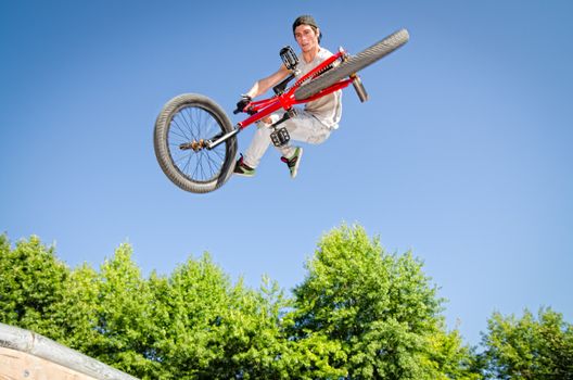 Bmx rider performing a tail whip at a quater pipe ramp on a skatepark.