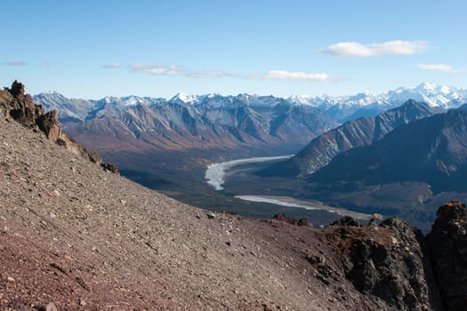 Rugged snow capped peaks rise above autumn lowlands