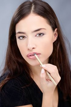 Woman applying cosmetic pencil on lips