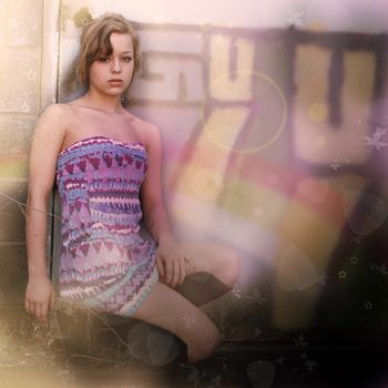 A young stylish woman poses next to some city graffiti.