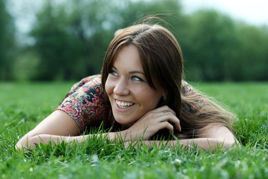 Portrait of young woman lying on a green lawn