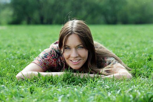 Portrait of young woman lying on a green lawn