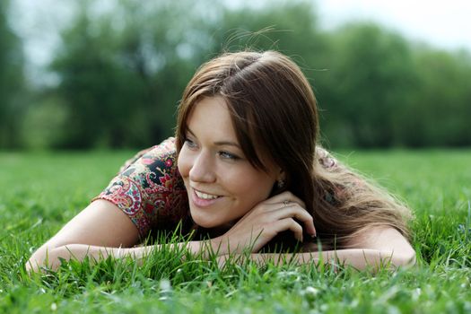 Portrait of young woman lying on a green lawn