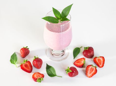 Strawberry milkshake with mint leaves, on white background.