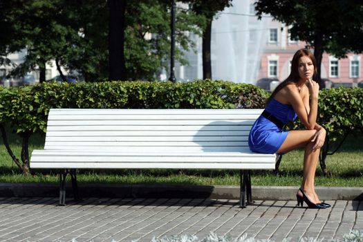 Beautiful young woman sitting on a park bench