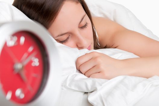 Woman sleeping in a bed with an alarm clock next to her