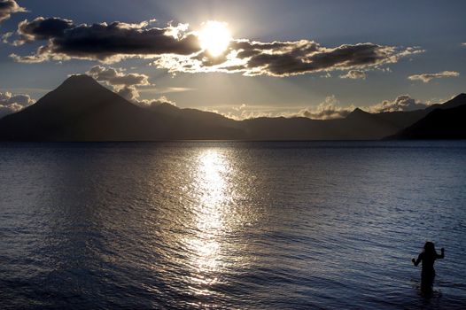  Volcanic Atitlan Lake in Guatemala with a woman at sunset