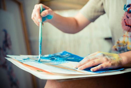 particular of woman painter hand painting in her studio