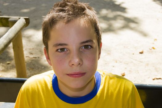 Cute boy smiling at camera in the park on a sunny day