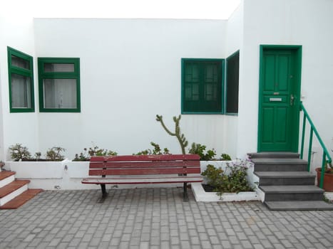 red bench in front of the wall and green door