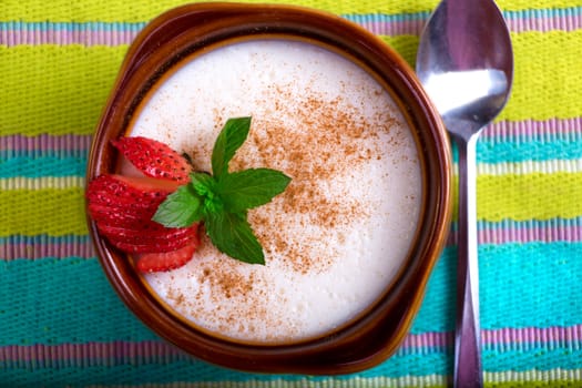 Turkish style rice pudding served in a crock and garnished with strawberry and mint leaves