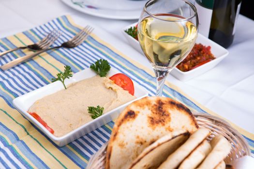 Hummus paired with white wine and pia breads and served on a blue striped cotton placement