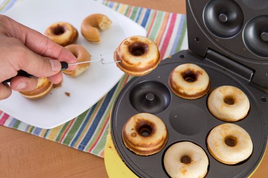 Clean hands baking mini donuts in the donut making machine