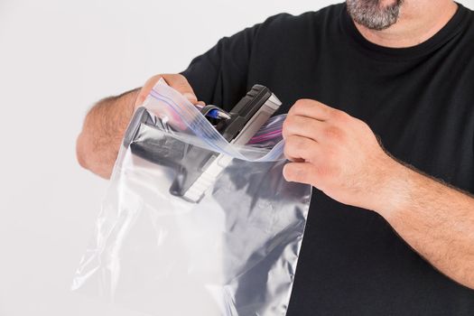 Crime scene investigator founds a gun, he is placing the gun in to a evidence bag carefully without touching for further analysis