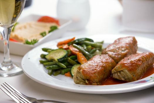 Turkish stuffed cabbage rolls served along with steamed green beans, carrots and zucchini, complemented with hummus plate and white wine.