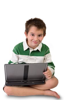 Elementary age boy sitting on the floor with crossed legs holding his laptop perhaps he is working on his homework or playing games you decide. Isolated on white background