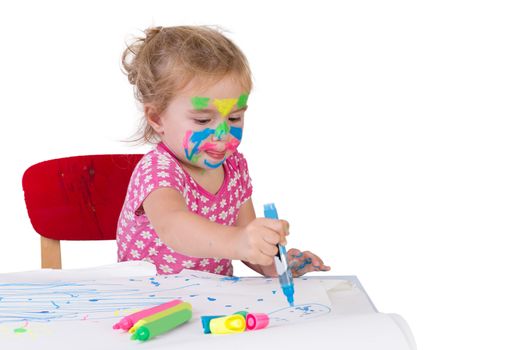 Toddler girl learning how to draw with coloring markers, her face painted with markers, isolated on white