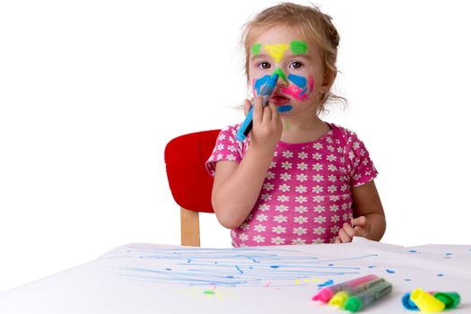 Toddler girl coloring her own face with colorful markers, hopefully they are not permanent