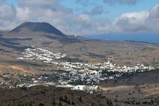 Small town in the desert near a volcan on a cloudy sky