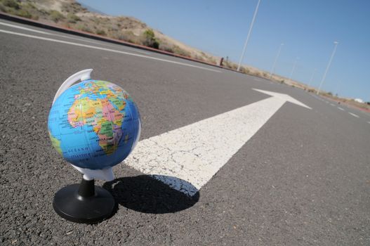 geographic globe and arrow on a asphalt street to the future