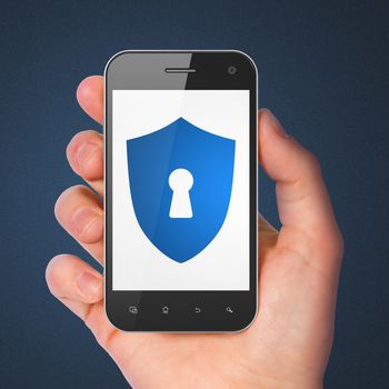 Safety concept: hand holding smartphone with Shield With Keyhole on display. Generic mobile smart phone in hand on Dark Blue background.