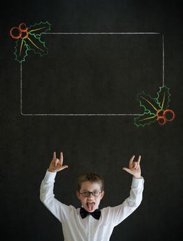 Knowledge rocks boy dressed up as business man with Christmas holly to do checklist on blackboard background