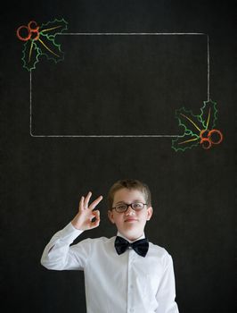 All ok or okay sign boy dressed up as business man with Christmas holly to do checklist on blackboard background