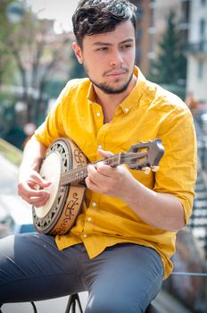 hipster young man playing banjo in the city