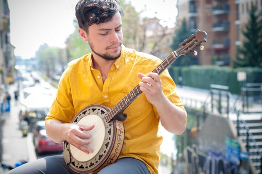 hipster young man playing banjo in the city